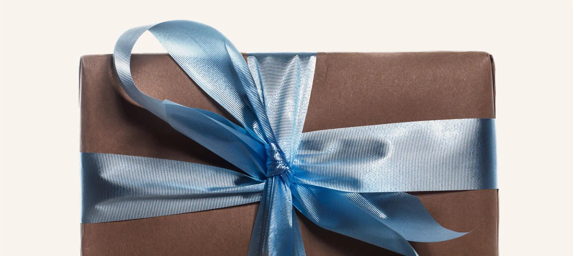 A brown gift box wrapped with a shiny light blue satin ribbon tied into an elegant bow.